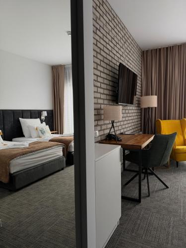 a hotel room with a bed and a desk and a table at Hotel Alhar in Lubliniec