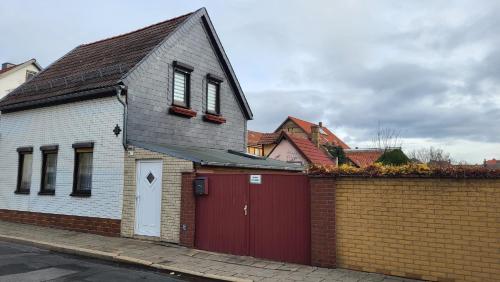 a house with a red garage and a brick wall at Ferienhaus Rosengarten in Blankenburg