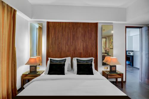 a bedroom with a large white bed with two lamps at Palette Hotel Seminyak in Seminyak