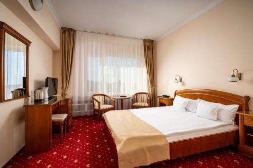 a hotel room with a bed and a desk and a window at Hotel Traian in Brăila