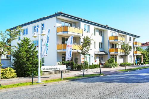 a large white building with balconies on a street at Ferienwohnung Quartier18-09 strandnah in Karlshagen