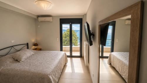 a bedroom with two beds and a door to a balcony at Alia Beachfront Penthouse with Sea View in Lefkandi Chalkidas