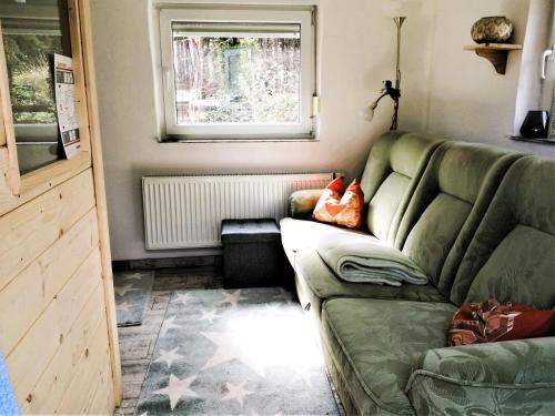 a living room with a green couch and a window at Ferienwohnung Hänsch in Siedlung Adler