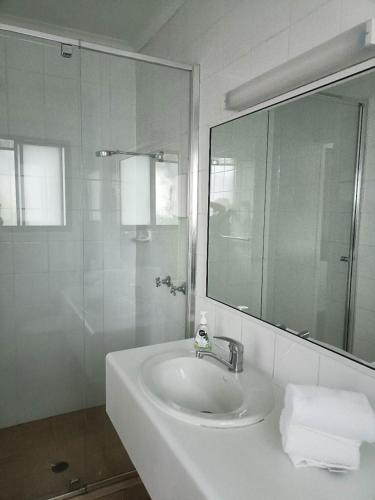 a white bathroom with a sink and a mirror at Motel in Nambour in Nambour
