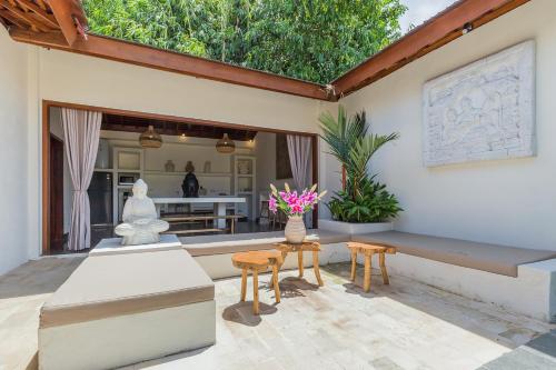 a patio with two chairs and a table with flowers on it at Tropical Villas Complex in Jimbaran