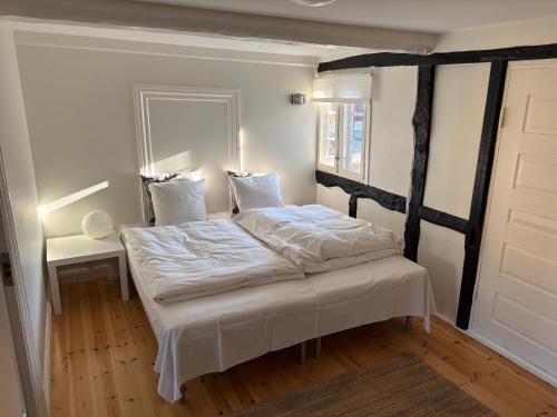 a bedroom with a bed with white sheets and a mirror at Købmandsgården, Ballen in Ballen