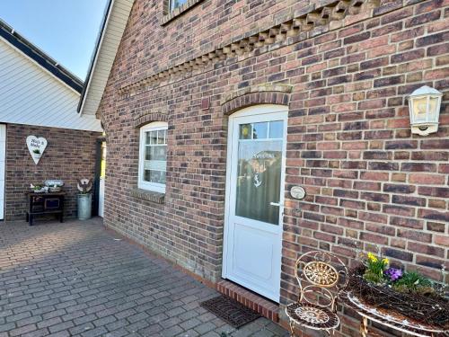 a brick building with a white door and a bench at Ferienwohnung Petersen in Nordstrand