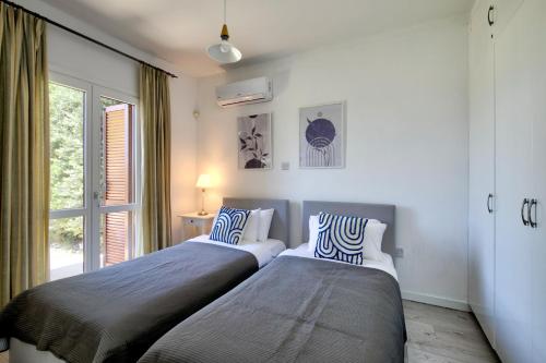 two beds in a room with a window at Beautiful Junior Villa GZ01, next to Communal Pool, Aphrodite Hills in Kouklia
