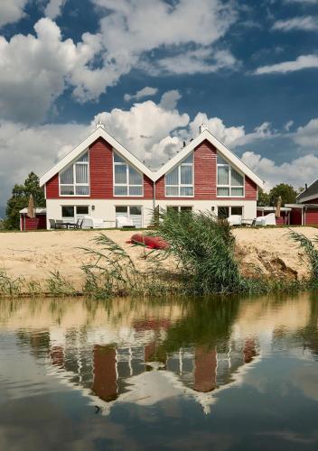 a red and white house next to a body of water at Ferienhaus Pier 85 in Nordhorn