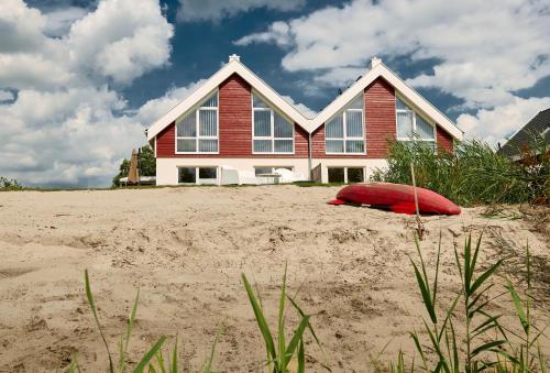 a house on the beach with a red pillow in the sand at Ferienhaus Pier 85 in Nordhorn