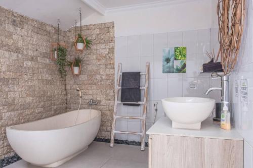 a bathroom with a white tub and a sink at Villa Karma Legian in Legian