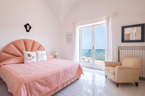 a bedroom with a bed and a chair and a window at Tra Cielo e Mare & La Dépendance - Fantastic Sea View in Anacapri