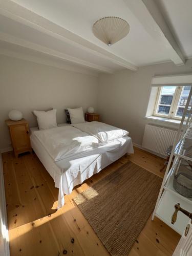 a bedroom with a large white bed and a window at Købmandsgården, Ballen in Ballen
