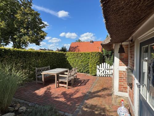 a patio with a table and chairs and a fence at Ferien unterm Reetdach in Stade