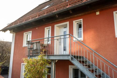 a red building with a staircase on the side of it at Ferienwohnung Demmelbach in Weil