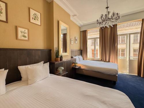 a hotel room with two beds and a chandelier at Hotel Botaniek in Bruges