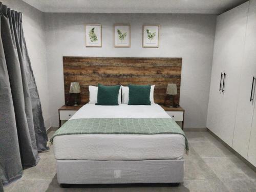 a bedroom with a large bed with green pillows at Phumlani Village Lodge in White River
