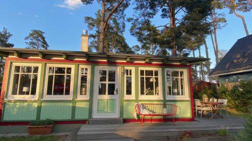 a tiny house with a deck and a chair at Ferienhaus Kienhus in Graal-Müritz