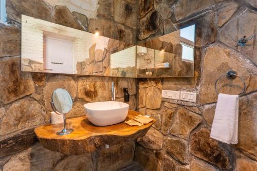 a stone bathroom with a sink and a mirror at Seclude Ramgarh Cliff's edge in Rāmgarh