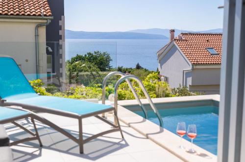 a patio with a chair and wine glasses next to a swimming pool at VILLA SOLIS LACUS modernes Apartment - privater beheizbarer Pool- Klimaanlage - private Parkplätze in Njivice