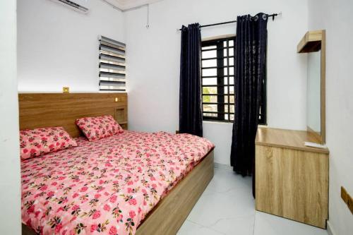 a bedroom with a bed with pink sheets and a window at Famous Apartments in Ologode