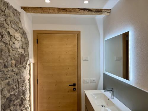 a bathroom with a sink and a wooden door at Alpine Grace in Falcade
