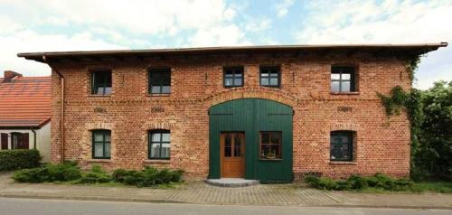 a brick building with a green door on a street at Fewos Storchenhof am Kummerower See in Meesiger