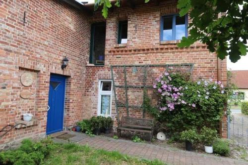 a brick house with a blue door and a bush at Fewos Storchenhof am Kummerower See in Meesiger