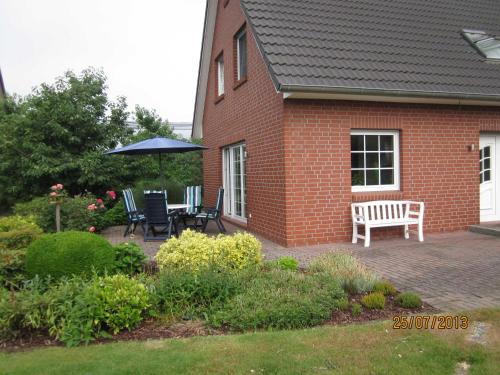 a brick house with a table and chairs and an umbrella at Ferienhaus Minners in Jork