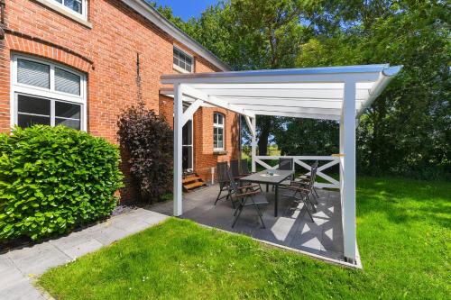 a patio with a table and chairs under a white canopy at Ferienwohnung Landleben am Meer in Bensersiel