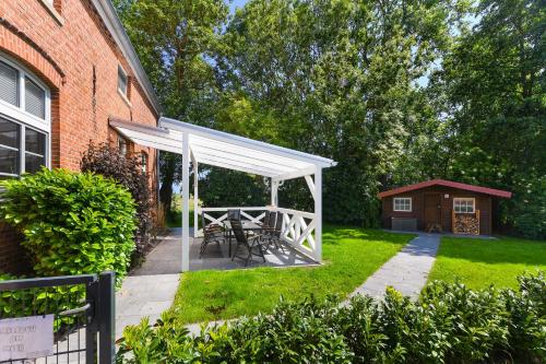 a white pergola with a table and chairs in a yard at Ferienwohnung Landleben am Meer in Bensersiel