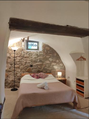 a bedroom with a large bed in a stone wall at Can Canals (Rectoria de Dosquers) in Maia de Montcal
