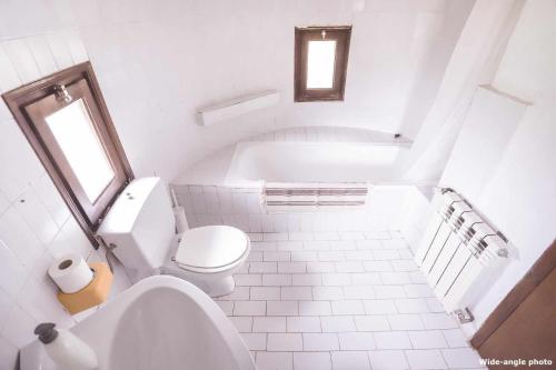 a white bathroom with a toilet and a bath tub at Can Canals (Rectoria de Dosquers) in Maia de Montcal