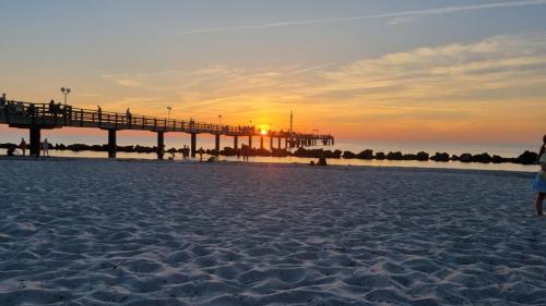 a pier on the beach with a person standing on the sand at An der Schmiedestraße Strandläufer in Wustrow