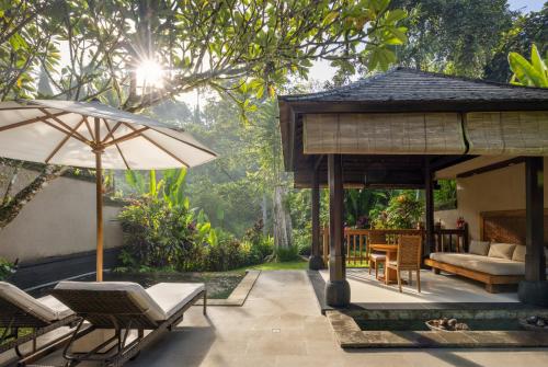 an outdoor patio with chairs and an umbrella at The Lokha Ubud Resort, Villas & SPA in Ubud