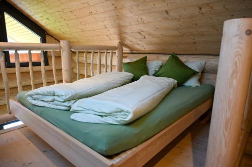 a bed in a log cabin with green and white pillows at Mein Refugium Luxury Tiny House in Unteriberg