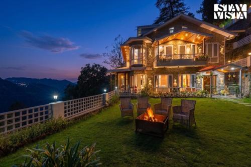 a house with a fire pit in the yard at Simla Manor by VEO - Part of StayVista in Shimla