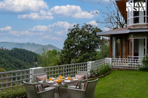 a table and chairs on a porch with a view of the mountains at Simla Manor by VEO - Part of StayVista in Shimla