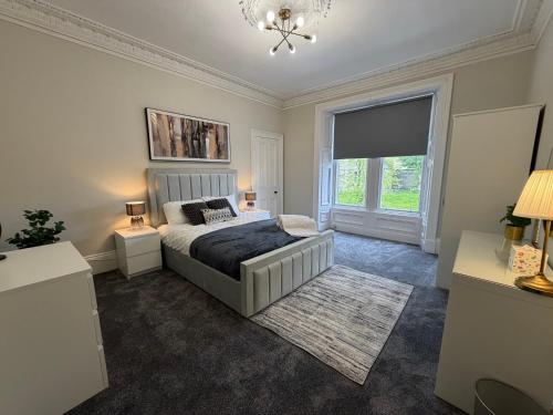 a bedroom with a bed and a window and a chandelier at Prime Dundee West End 3BR Apartment, Stunning River Views, Sleeps 6 in Dundee