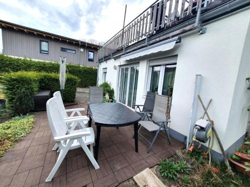 a patio with a table and chairs and a building at Ferienwohnung am Kittenbach in Utting am Ammersee