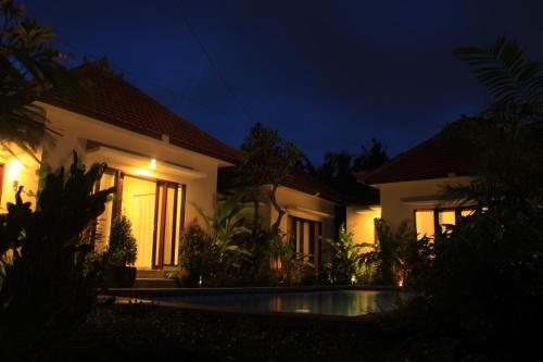 a villa with a swimming pool at night at Uma Budhas in Ubud