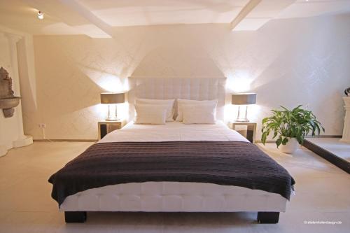 a bedroom with a large white bed with two lamps at Elements Hotel in Regensburg