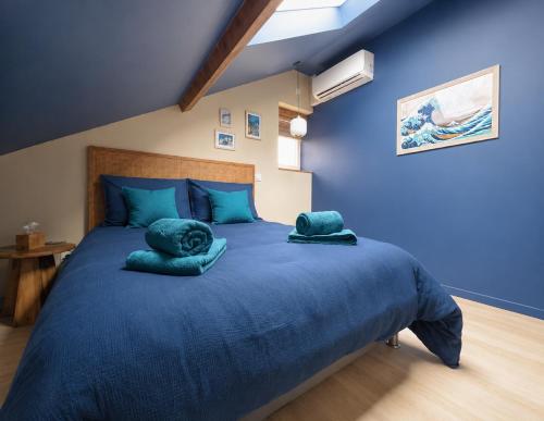 a blue bedroom with a large blue bed with two pillows at Élégant T3 moderne et central, parking inclus in Montargis