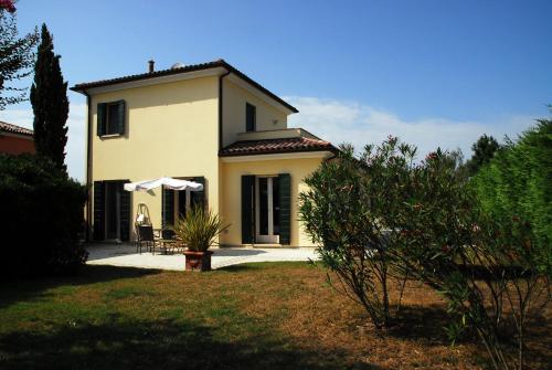 a small white house with an umbrella in a yard at Scirocco in Isola Albarella