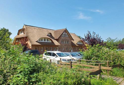 a large house with cars parked in front of it at Haus an der Düne WE 05 in Lobbe