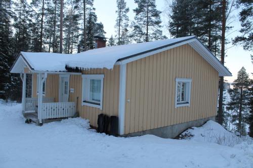 a small cabin with snow on top of it at Lake Cottage Jänisvaara in Kolinkylä