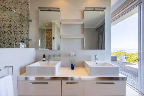 two sinks in a bathroom with a large mirror at Seascape in Plettenberg Bay