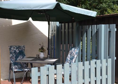 a white picket fence with a table and an umbrella at Neue moderne Ferienwohnung, separater Eingang, Seenähe in Möllen