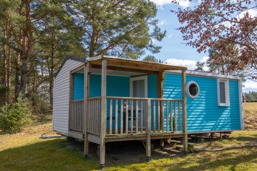 a blue tiny house with a porch in a field at Mobilheime Lagune in Lychen