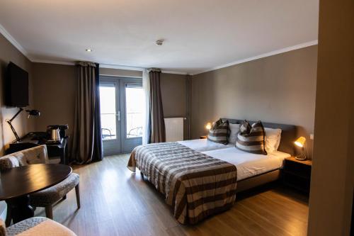 ein Hotelzimmer mit einem Bett und einem Tisch in der Unterkunft Hotel Gulpenerland in Gulpen-Wittem